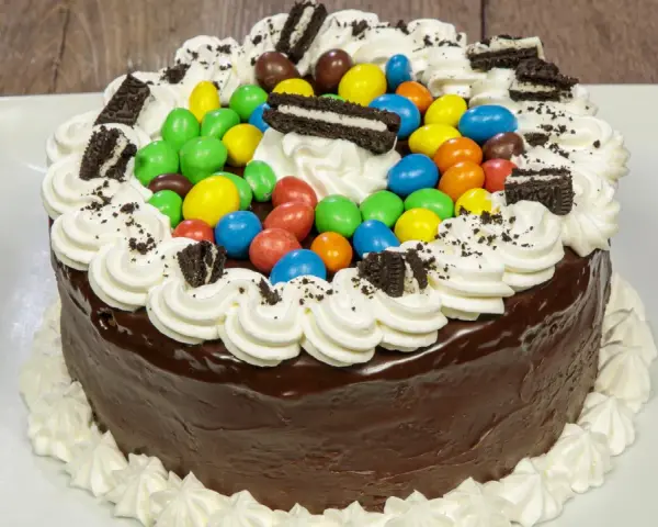 Torta al cioccolato con panna, caramelle colorate e biscotti Oreo, un'esplosione di gusto per torte di compleanno particolari.