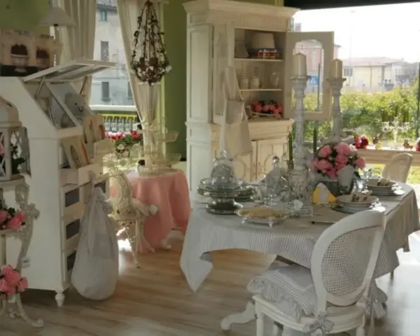 Un tavolo apparecchiato in **stile provenzale francese**, con sedie bianche, candelabri e fiori rosa.