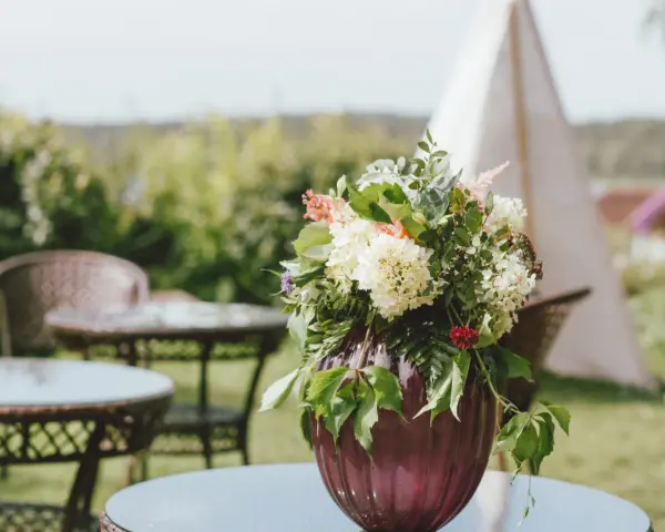 Un hermoso arreglo de flores en un jarrón morado, perfecto para celebrar un feliz día del Carmen.