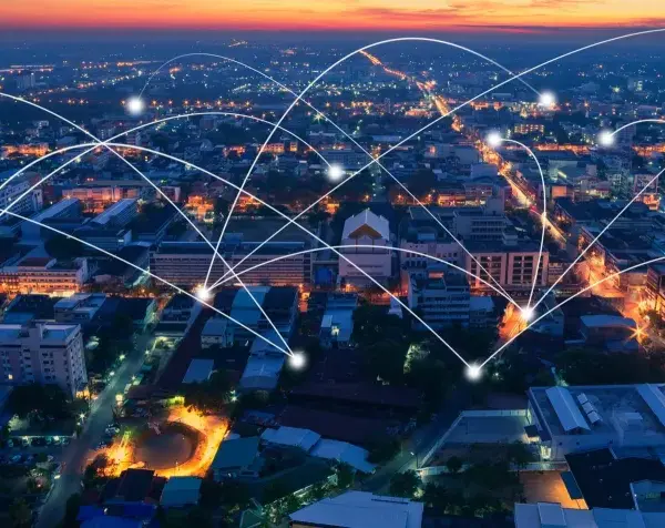 Aerial view of a city at dusk, with glowing lines connecting buildings, symbolizing modern infrastructure and networking.