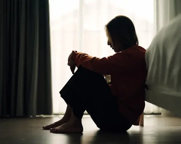 Ein Mädchen sitzt traurig auf dem Boden, die Knie angezogen. Die Szene könnte die emotionale Achterbahnfahrt bei borderline bei Kindern darstellen.