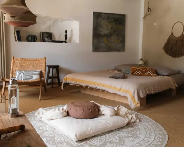Ein gemütlicher Raum zum Meditieren einrichten: Ein Bett, ein Stuhl, Kissen und Decken laden zur Entspannung ein.