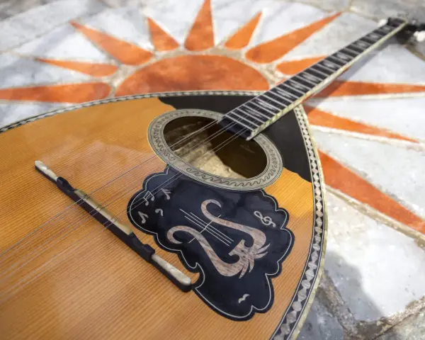 Piękny grecki instrument muzyczny, bouzouki, leży na mozaice z symbolem słońca.