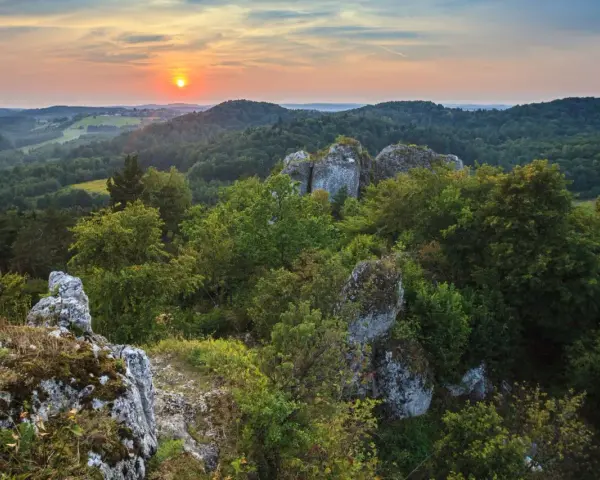 Zachód słońca nad Górami Świętokrzyskimi. Skaliste formacje i bujna zieleń tworzą malownicze krajobrazy, jedne z wielu atrakcji regionu.