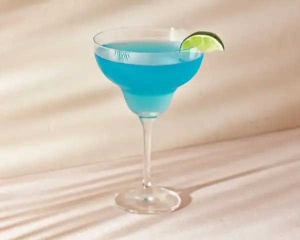 Niebieski drink z ginem, tonikiem i blue curacao, ozdobiony plasterkiem limonki, wygląda orzeźwiająco.