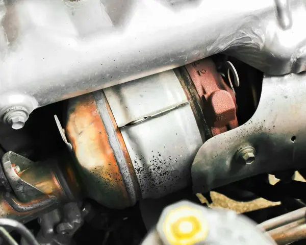 Dettaglio del sistema di scarico di un'auto, con il filtro antiparticolato (FAP) visibile. Togliere il FAP vantaggi: meno intasamenti, migliore fluidità dei gas.