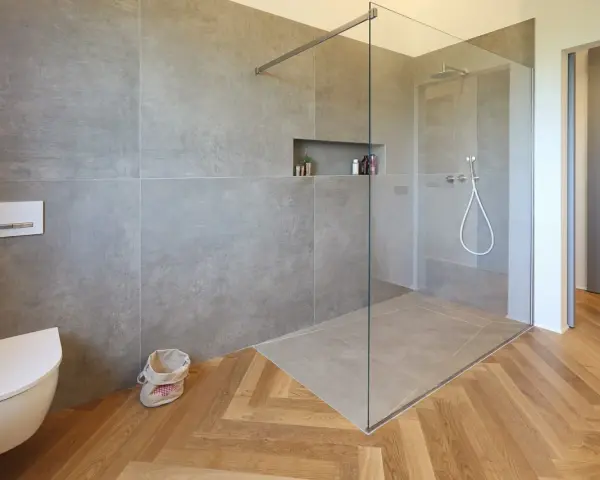 Bagno moderno con doccia walk-in, vaso sospeso e finiture in legno. Il significato di doccia walk-in è uno spazio aperto e accessibile.
