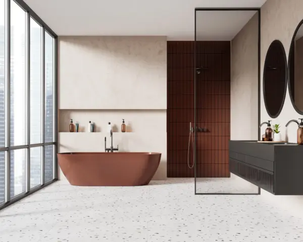 Salle de bain moderne avec baignoire rouille, douche en briques rouges et lavabo suspendu. Le sol en terrazzo offre une belle dimension carrelage.