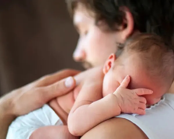Padre abbraccia neonato. Osservare attentamente i sintomi autismo nel neonato di 3 mesi, come la mancanza di contatto visivo o risposte emotive atipiche.