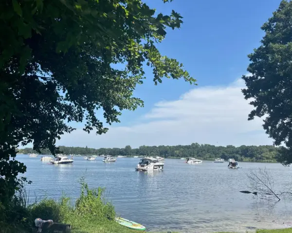 Boote auf dem Glindower See unter blauem Himmel, umgeben von grünen Bäumen. Ein sonniger Tag am Wasser.