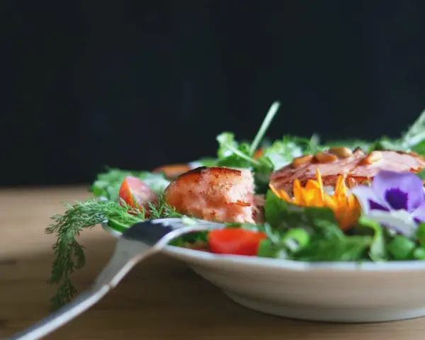En vacker sallad med lax, tomater och ätbara blommor. Perfekt för att deffa mat och njuta av en hälsosam måltid.