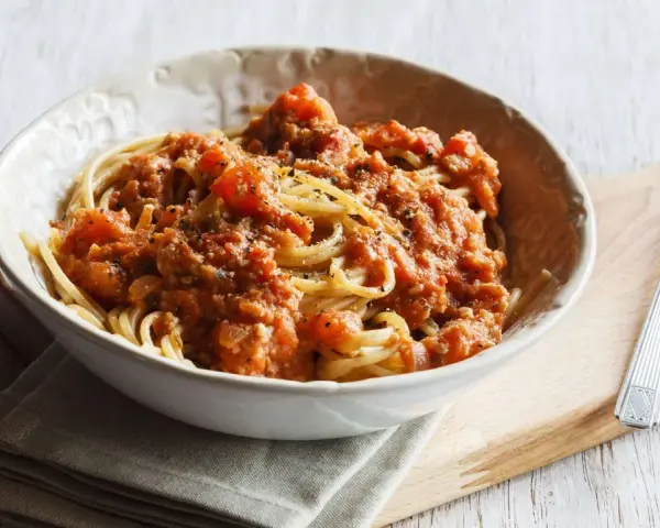 Eine Schüssel Spaghetti mit einer herzhaften, tomatigen Bolognese-Sauce, perfekt für eine schnelle Mahlzeit.