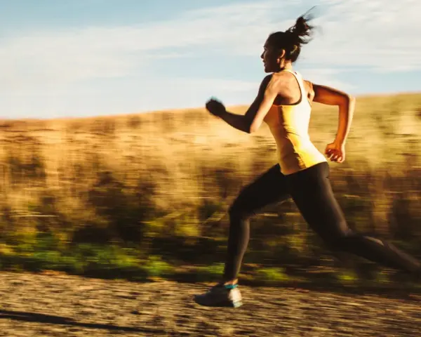 Kvinna springer i full fart, ett intensivt hiit pass utomhus.
