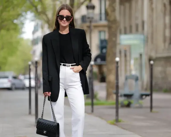 Donna con blazer nero, jeans bianchi e borsa Chanel, un look che aiuta a sembrare più alto.