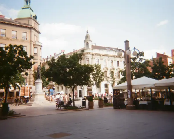 Spacer z kawiarnianymi stolikami i ludźmi, uchwycony aparatem Kodak M35.