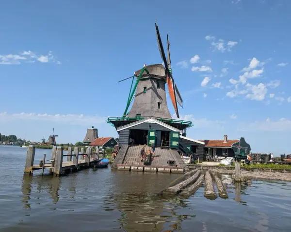 Wiatraki w Zaanse Schans nad wodą, z drewnianym pomostem i łódkami.
