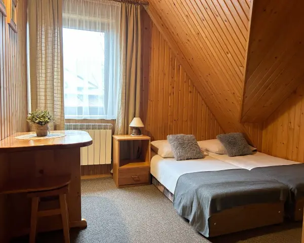 Pokój w stylu góralskim, idealny na wypoczynek u Lucyny Białka Tatrzańska. Dwa łóżka, drewniane meble i przytulna atmosfera.