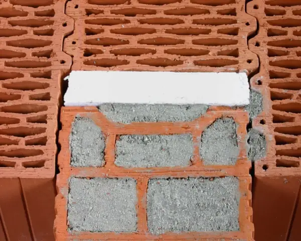 Zbliżenie na pustaki ceramiczne z widocznymi pustymi przestrzeniami i zaprawą. Pokazane są wymiary pustaka i sposób ich układania.