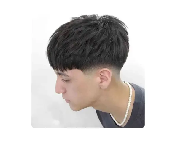 Joven con corte de pelo moderno, un low fade hombre con la parte superior texturizada y flequillo recto.