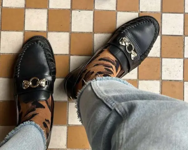 Elegantes mocasines negros con detalle de tigre en los calcetines, un ejemplo de los diversos tipos de mocasines.