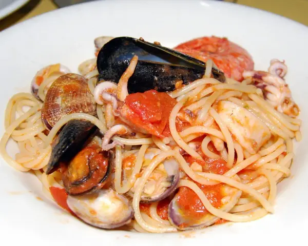 Spaghetti allo scoglio con cozze, vongole, calamari e pomodoro. Un piatto di mare ricco e saporito.