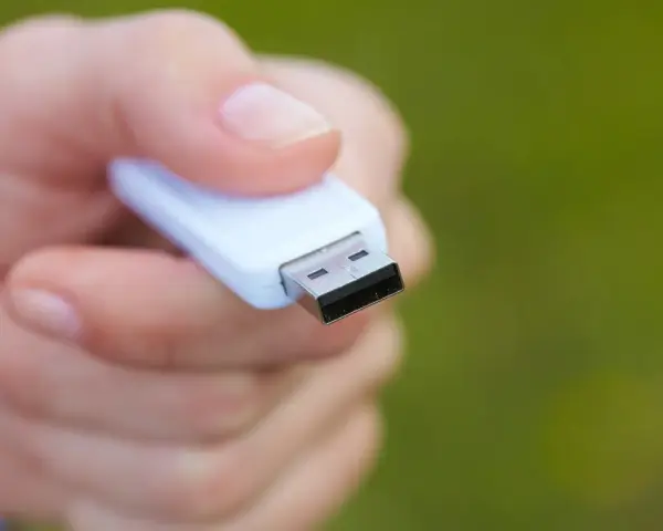 Dłoń trzyma biały pendrive, gotowy do formatowania NTFS.