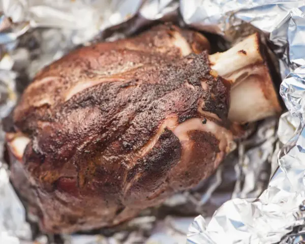 Stinco di maiale succulento, cotto alla perfezione e avvolto in carta stagnola, pronto per essere gustato.