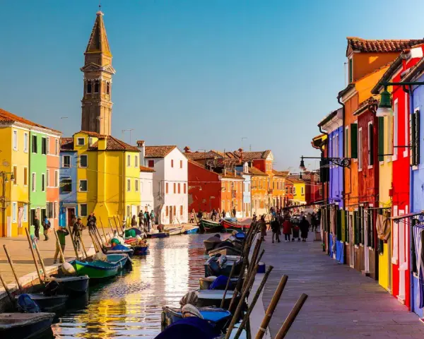 Coloratissima città lagunare con case vivaci, canali e barche ormeggiate.