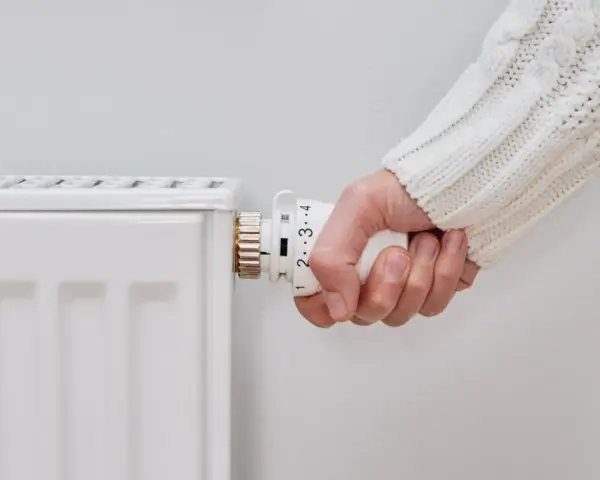 Mano girando la perilla del radiador para saber como encender la calefacción desde la caldera.