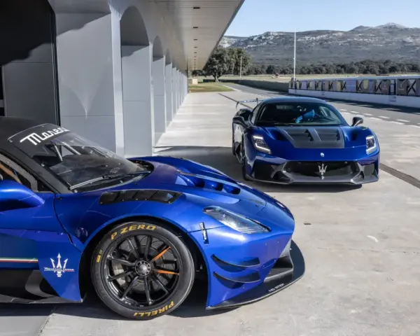 Dwa niebieskie Maserati na torze wyścigowym. Jedno z nich, z bliska, ma na oponach napis Pirelli P Zero.