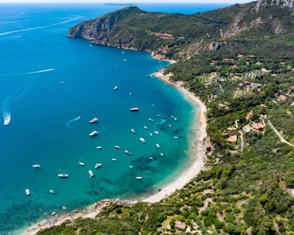 Baia con acque cristalline e numerose barche. Ville immerse nel verde e sentieri panoramici: ecco cosa vedere all'Argentario per una vacanza indimenticabile.