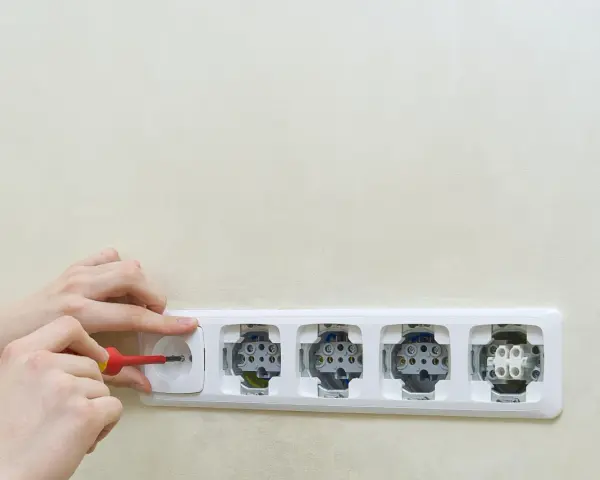 Ręce montują gniazdka elektryczne. Dowiedz się, jak podłączyć oświetlenie z gniazdka, wykonując te czynności.