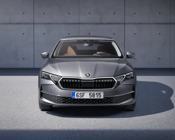 Nowa Skoda Octavia w szarym kolorze, z brązowym wnętrzem, prezentuje się elegancko na tle betonowej ściany.
