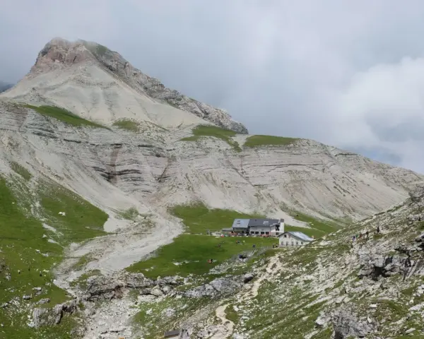 Rifugio alpino con escursionisti e gregge in un paesaggio montano mozzafiato, vicino a Passo Val Gardena.