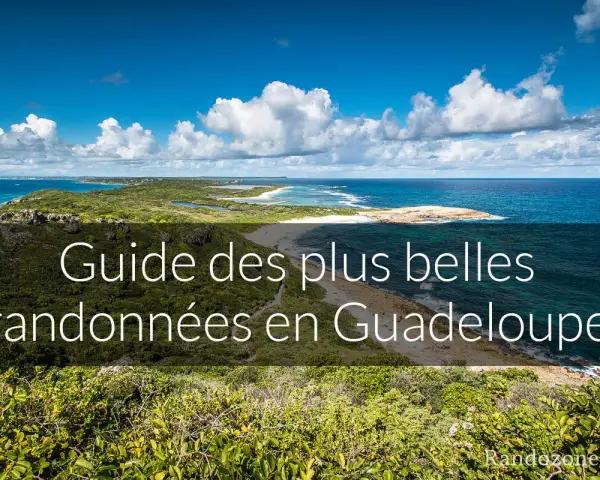 Paysage côtier luxuriant avec la mer bleue et des nuages blancs. Ce guide des plus belles randonnées en Guadeloupe vous invite à explorer ses montagnes verdoyantes.