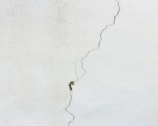 Crepa profonda su muro bianco, un segno per come distinguere le crepe pericolose.