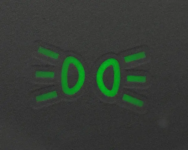 Zielony symbol świateł mijania na ciemnym tle.