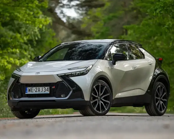 Nowy Toyota C-HR Hybrid w kolorze srebrno-czarnym na tle zieleni.