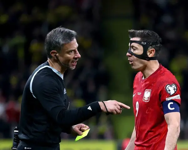 Sędzia pokazuje żółtą kartkę Robertowi Lewandowskiemu, jednej z legend piłki nożnej.