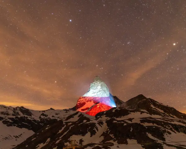 Górski szczyt, niczym polski Matterhorn, rozświetlony nocą polskimi barwami pod rozgwieżdżonym niebem.