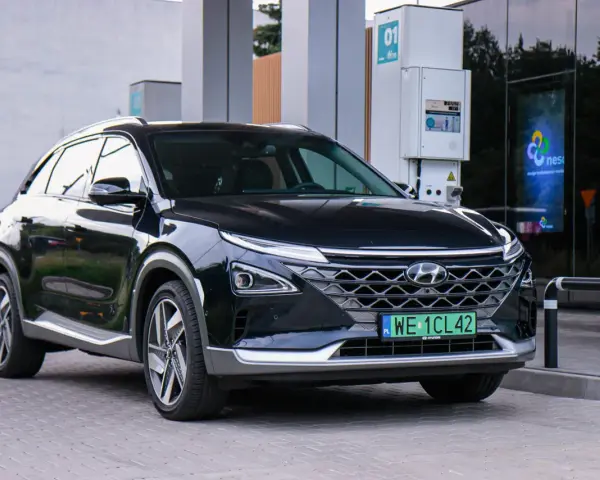 Czarny Hyundai Nexo, jeden z samochodów na wodór, tankuje na stacji.