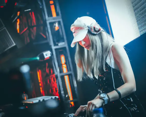DJane legt auf, die Menge tanzt zu fetter electro dance music. Rote Lichter blitzen, die Musik pulsiert.