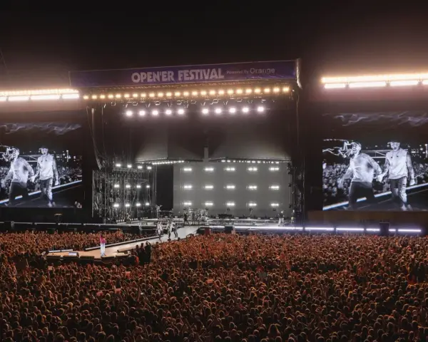 Ogromny tłum na Opener Festival, **ile ludzi**! Na scenie artyści, a na telebimach ich wizerunki.