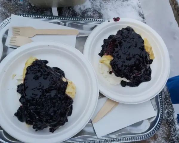 Dwa talerze z naleśnikami i jagodami, gotowe do zjedzenia w górskiej chatce.