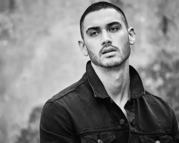 Hombre joven con un corte de pelo buzz cut, viste chaqueta vaquera oscura. Mirada intensa.