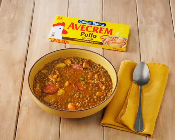 Un tazón de lentejas estofadas con chorizo y patatas, junto a un paquete de Avecrem Pollo.