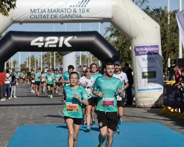 Corredores cruzan la meta de la distancia media maratón en Gandía.