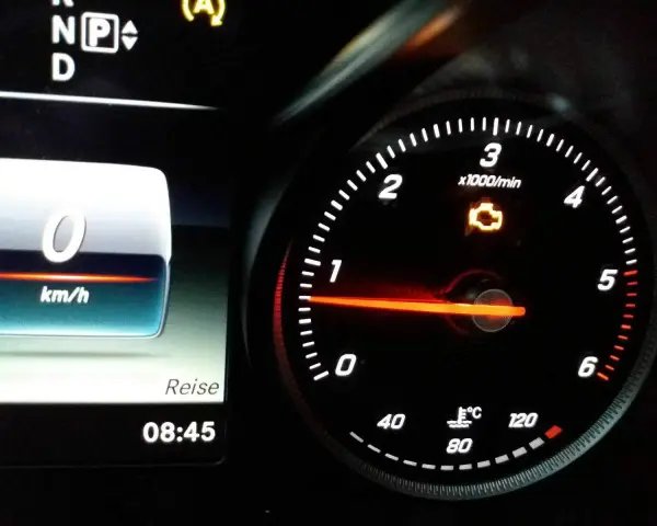 Gelbe motorkontrollleuchte leuchtet auf dem Armaturenbrett. Der Tachometer zeigt 0 km/h.