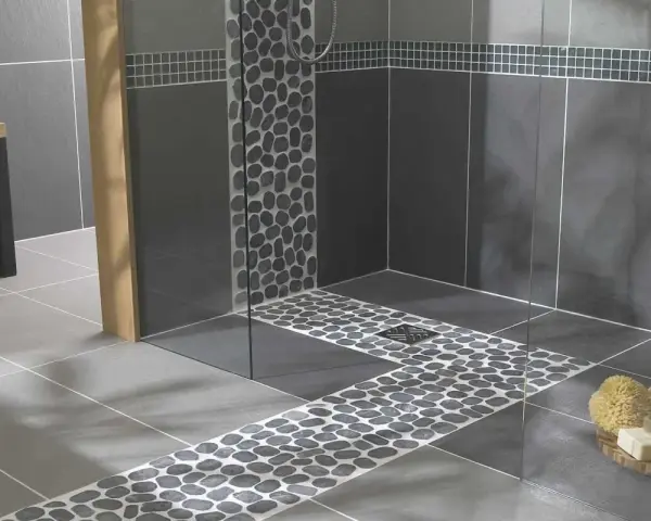 Carrelage moderne avec un chemin de galets sur le receveur de douche, créant une ambiance zen.
