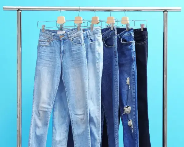 Różne modele jeansów na wieszakach. Czy rozmiar 27 spodnie damskie to Twój idealny rozmiar?